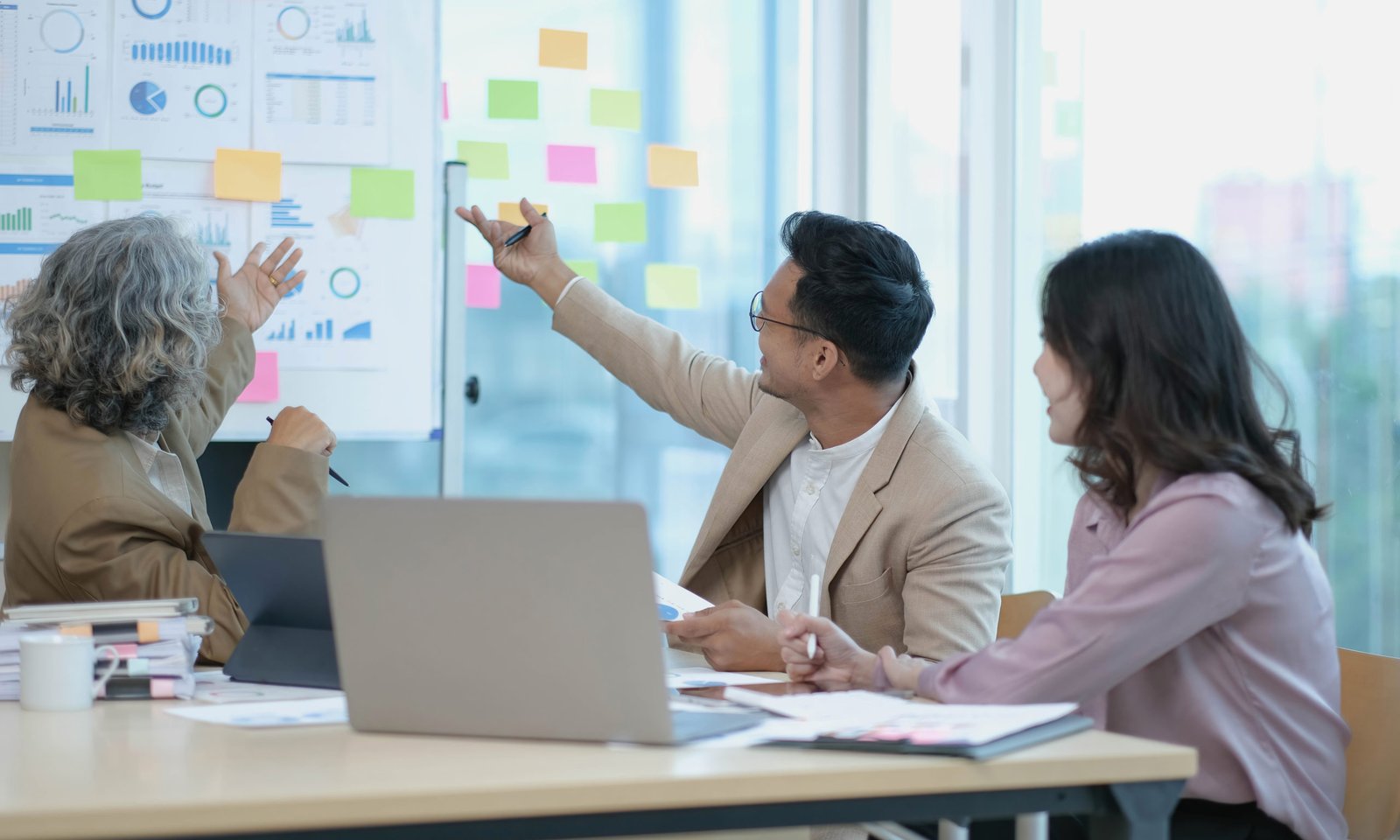 Group of Asian business people discuss together in team brainstorm meeting, work late night in office. Corporate business, coworker teamwork, financial consultant, or young entrepreneur concept premio ambev scaled 1